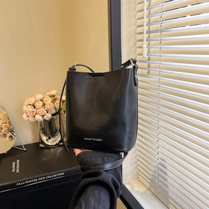 Dettaglio di una borsa a secchiello minimalista in pelle nera con scritta e trama