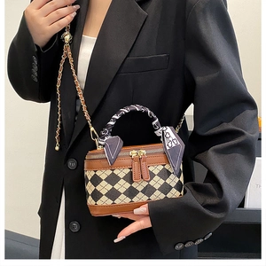 Close-up of quilted crossbody bag with gold chain strap and decorative silk scarf handle