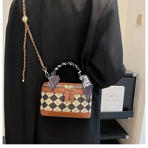 Close-up of quilted canvas box bag with brown leather trim and silk scarf handle