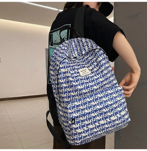 Detail of white canvas backpack with blue handwritten print and adjustable straps