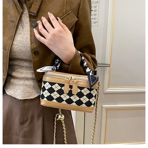Detail of box-shaped crossbody bag with quilted pattern, silk scarf handle, and gold chain
