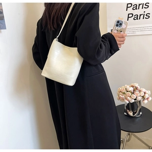 Dettaglio della borsa a secchiello minimalista in pelle crema con logo inciso
