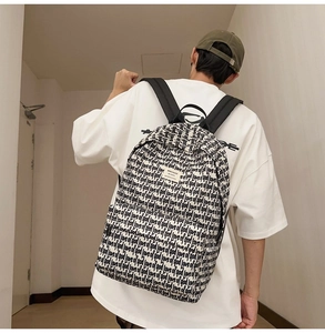 Detail view of stylish beige backpack with black 'love of god' print and wide straps