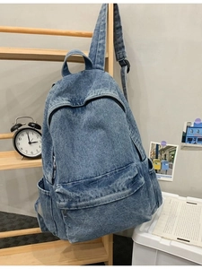 Light blue denim backpack with multi-pocket design hanging on a wooden ladder frame