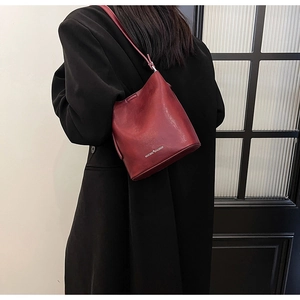 Vista dettagliata di una borsa a secchiello bordeaux con trama in pelle e marchio
