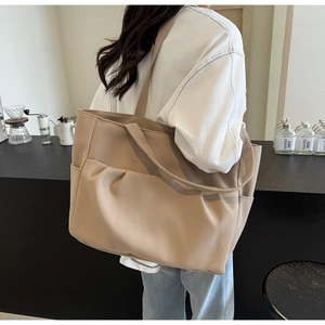Detail of beige large capacity tote bag featuring side pockets and side-view texture