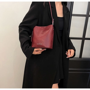 Dettaglio della borsa a secchiello in pelle rosso scuro con logo MUCOOU FASHION
