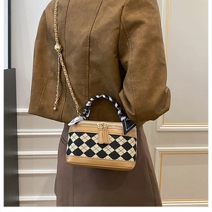 Detailed view of checkered box bag with printed silk scarf handle and gold chain strap