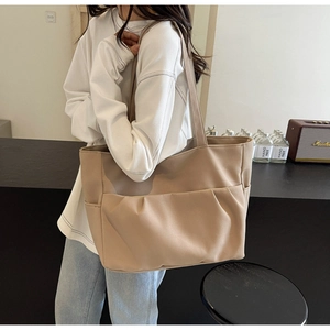 Close-up of khaki leather tote bag with pleated pocket shown in a lifestyle setting