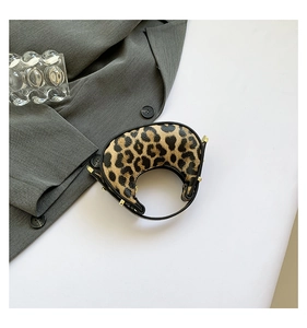 Detailed top view of leopard print crescent bag with metal rivets on a white surface