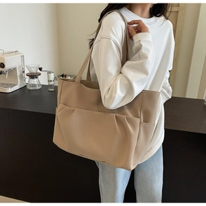 Detailed view of khaki tote bag with front accordion pockets and wide shoulder strap