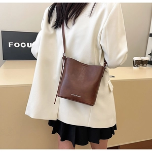 Dettaglio di una borsa a secchiello vintage in pelle marrone scuro con tracolla