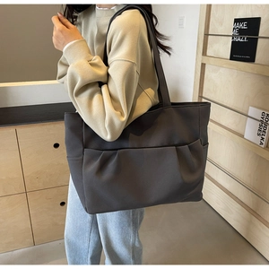 Detail of dark grey tote bag featuring functional pleated front pocket and large capacity