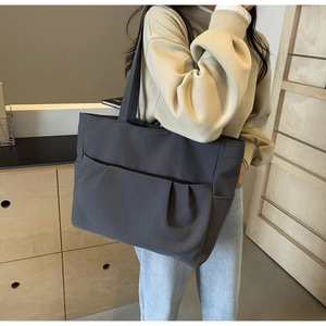 Close-up of dark grey large capacity tote bag with functional exterior pleat pockets