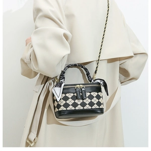 Close-up of a mini quilted crossbody bag with silk scarf handle and golden chain strap