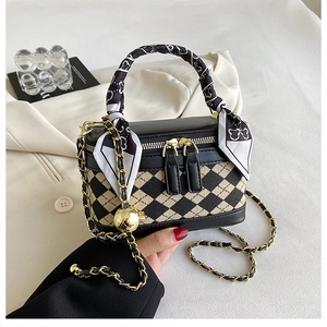 Close-up of yellow checkered bag with gold chain strap and decorative silk scarf
