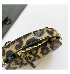 Macro shot of leopard print handbag featuring golden metal zipper and textured faux leather