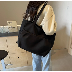 Side view of the large black tote bag showing side pocket and spacious interior on model