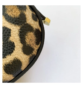 Detail of leopard print crescent bag showing faux leather texture and gold hardware