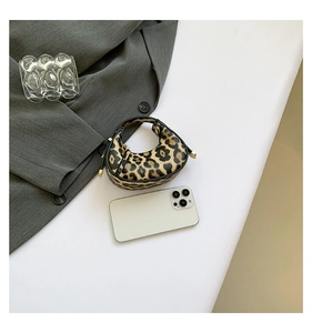 Flat lay of mini leopard print crescent bag with leather handles and gold hardware