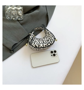 Mini leopard print crescent handbag with gold hardware next to a smartphone for size