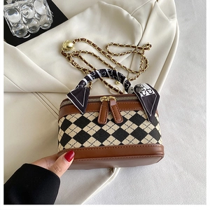 Detailed shot of quilted canvas handbag with brown leather trim and silk scarf handle