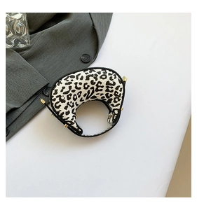 Top view of mini crescent leopard print handbag next to a blazer and glass cup
