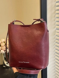 Borsa a secchiello in pelle bordeaux minimalista con scritte argentate e tracolla