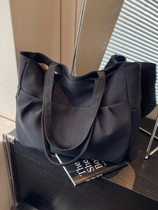 Minimalist black oversized tote bag with pleated side details for daily commuting