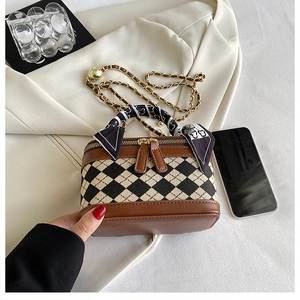 Detailed view of quilted chain bag with silk scarf handle and vintage metal zipper