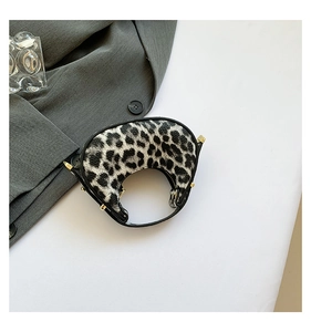 Detail of leopard print crescent bag with golden hardware and leather piping finish