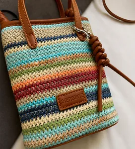 Detail der bunten Regenbogen-Strohtasche mit braunem Lederbesatz und Metallbeschlägen