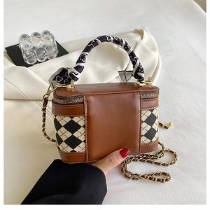 Detail of silk scarf wrapped handle on a quilted brown vanity bag with gold chain