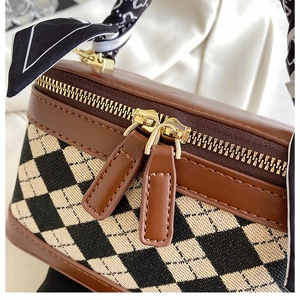 Detail of a brown leather and quilted fabric vanity bag with gold zippers and a silk scarf
