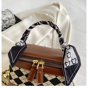 Detail of checkered crossbody bag with silk scarf handle and golden hardware finish