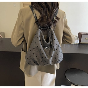 Détail d'un sac à dos gris à pois avec noeud métallique et fines bretelles en cuir noir porté