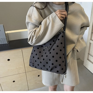 Détail du sac à bandoulière gris à pois avec nœud argenté porté par un mannequin
