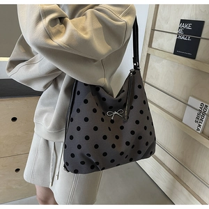 Vue détaillée du sac hobo gris à pois avec un nœud argenté délicat et une fine bandoulière noire
