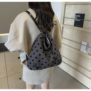 Détail d'un sac à dos gris à pois avec un nœud métallique noir sur un modèle