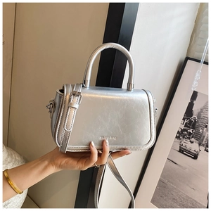 Close-up of silver crossbody bag with metallic finish and stylish round top handle