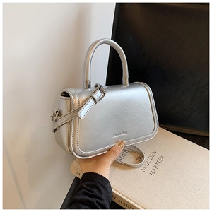 Detail of silver metallic handbag with decorative buckle and slim shoulder strap