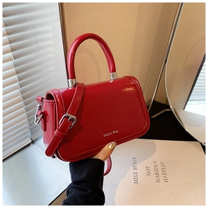 Detailed macro of a red glossy crossbody bag with cylindrical handle and Shiyu-Bag logo