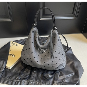 Détail d'un sac cabas rétro à pois avec breloque nœud argenté et anses noires