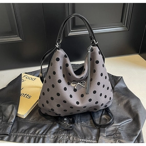 Détail du sac cabas gris à pois noirs avec nœud argenté et anses en cuir noir