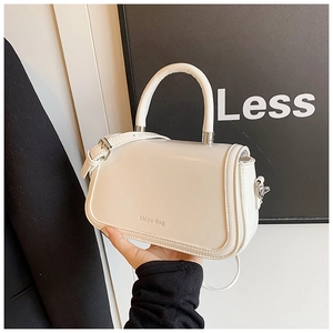 Close-up of a white minimalist handbag featuring silver hardware and a sleek shoulder strap