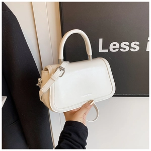 Detailed shot of a minimalist white leather crossbody bag with round handle and logo