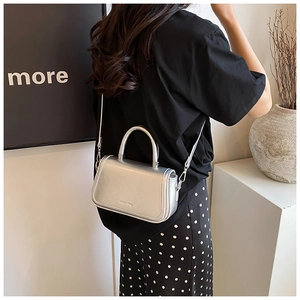 Detail of silver metallic crossbody bag with magnetic flap and embossed logo