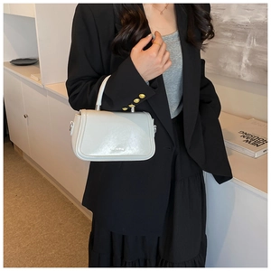 Detail of light blue glossy leather handbag with silver hardware and curved handle