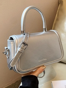 Metallic silver crossbody handbag with top handle and adjustable strap in minimalist style