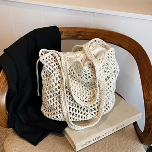 Detail of hollow woven cotton tote bag with beige drawstring inner pouch on wooden chair